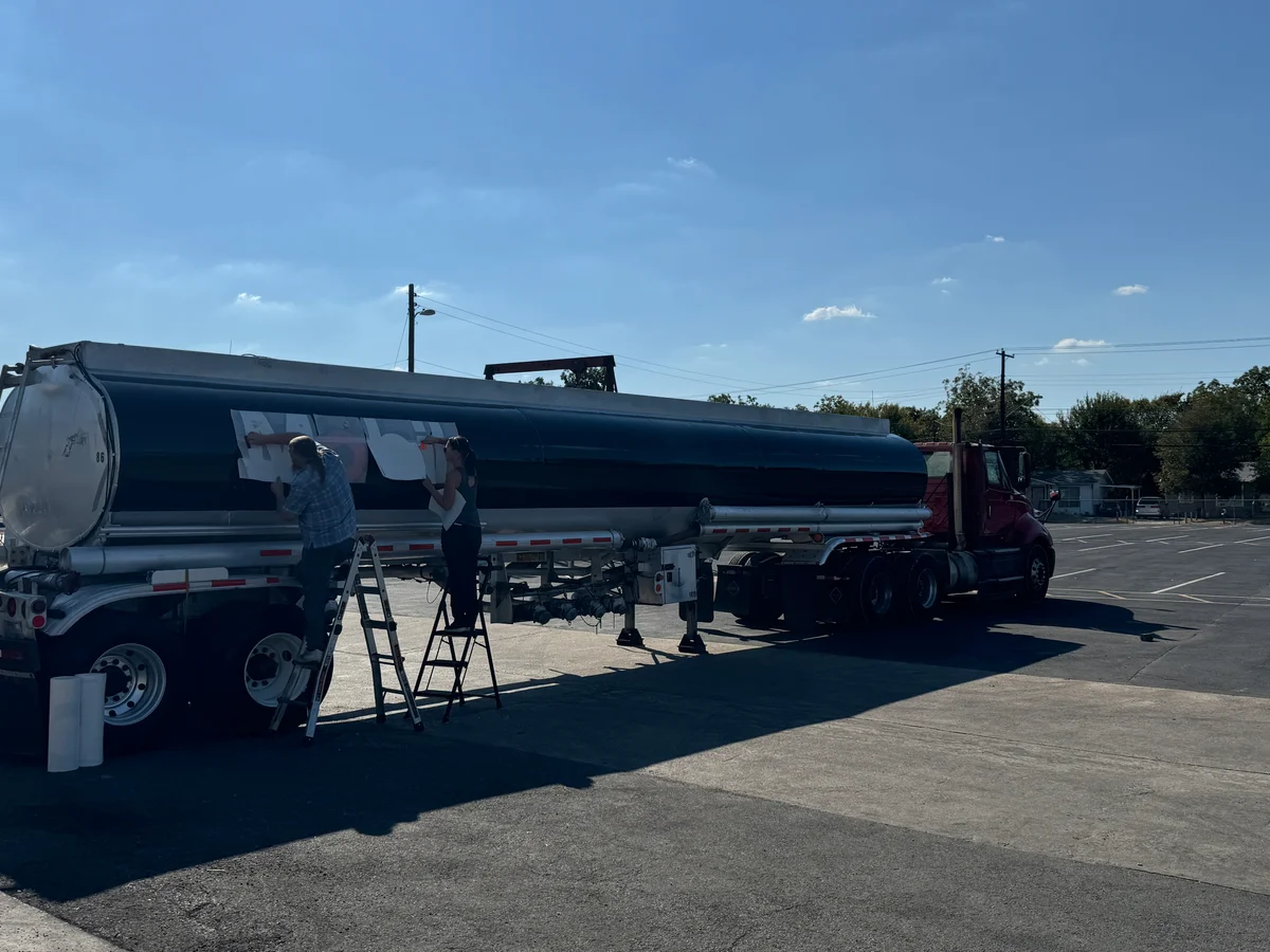 Dark blue semi tanker with install crew on ladders