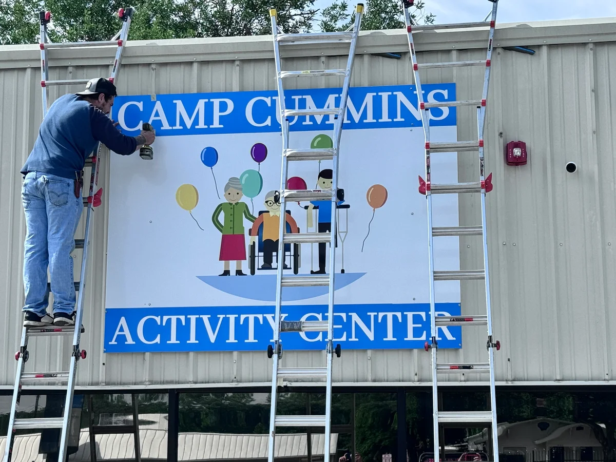 Worker installing Camp Cummins Activity Center sign